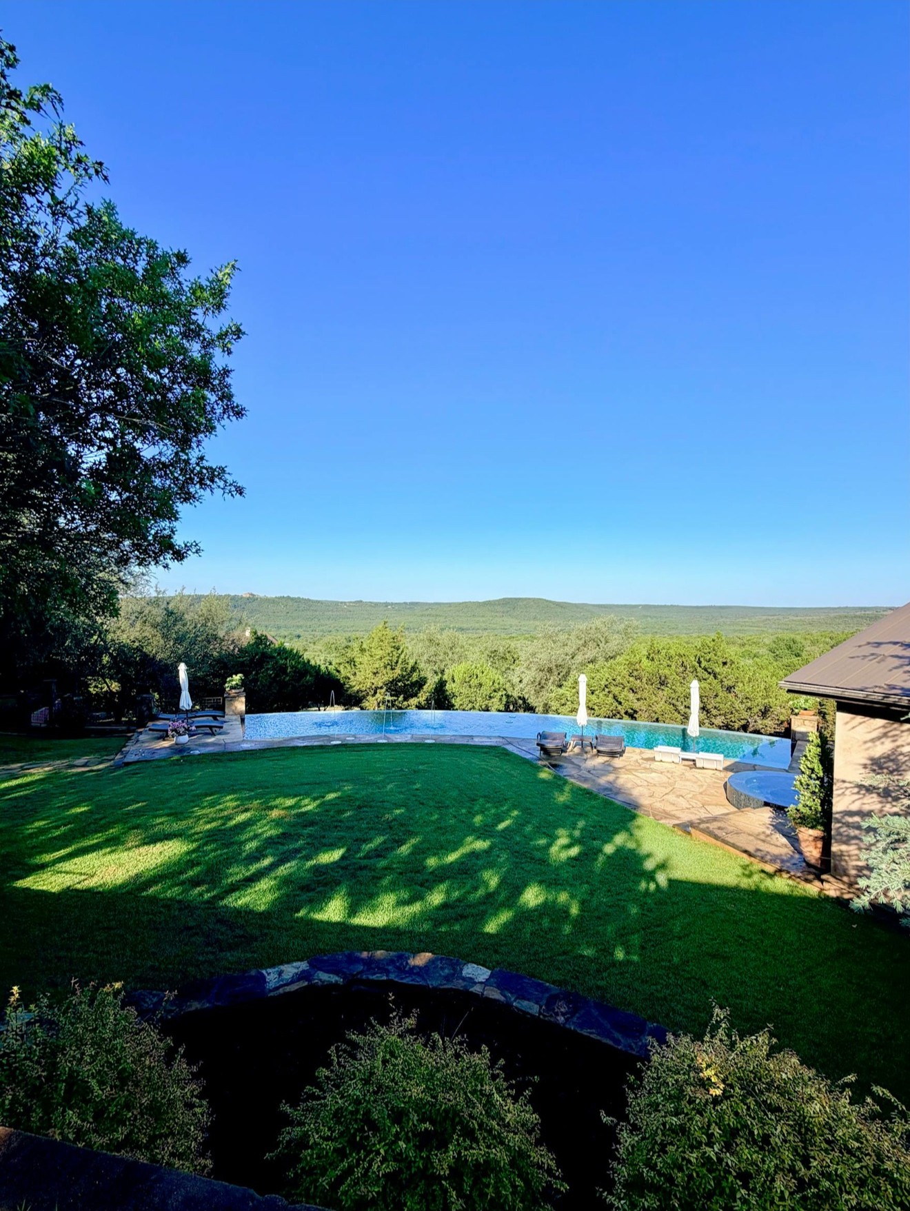 SORAE Estate panoramic view of the infinity pool, lawn, and rolling green hills